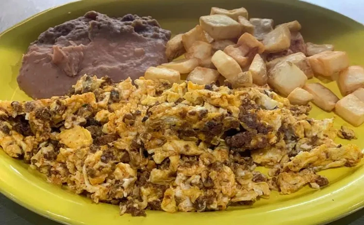 Steak, vegetables and eggs with potatoes and refried beans
